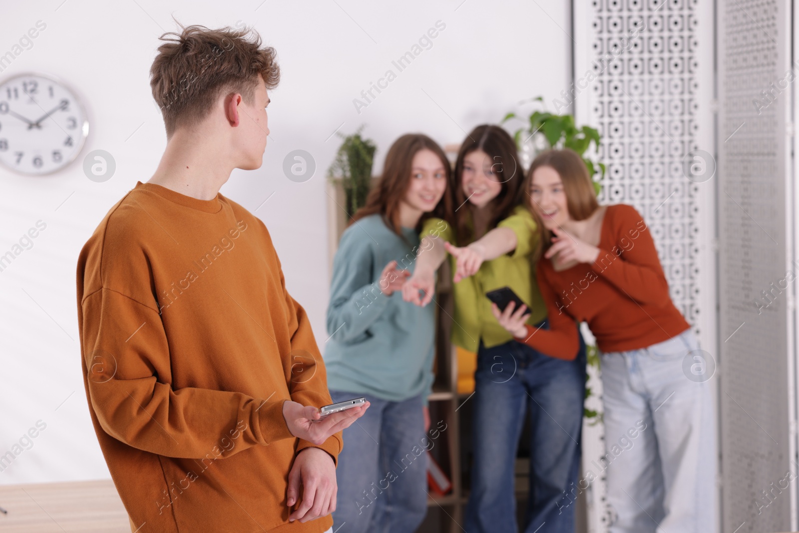 Teenage boy with smartphone suffering from bullying at school, selective focus Photo of Teenage boy with smartphone suffering from bullying at school, selective focus