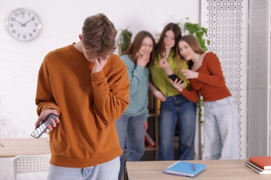 Photo of Teenage boy with smartphone suffering from bullying at school, selective focus