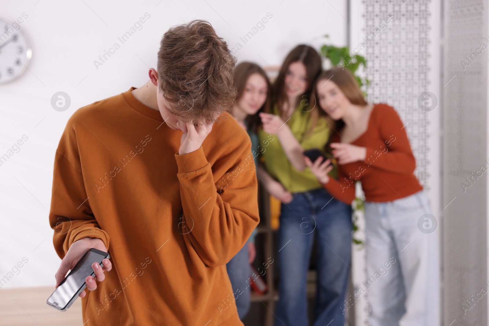 Teenage boy with smartphone suffering from bullying at school, selective focus Photo of Teenage boy with smartphone suffering from bullying at school, selective focus