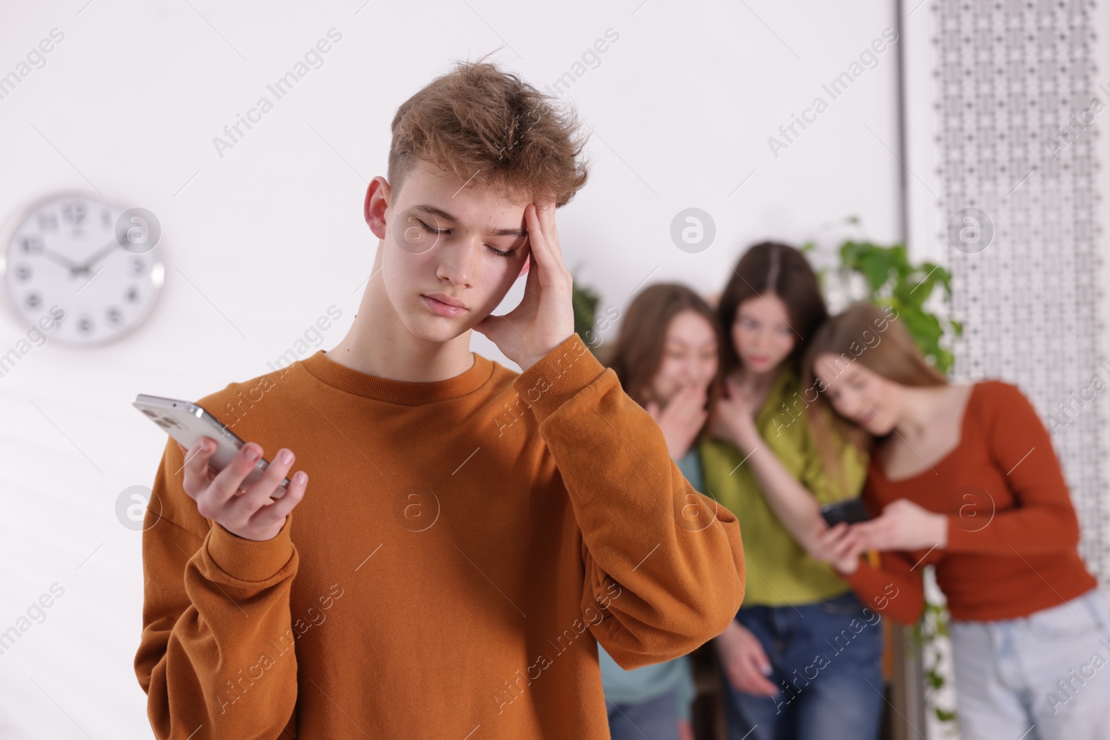 Teenage boy with smartphone suffering from bullying at school, selective focus Photo of Teenage boy with smartphone suffering from bullying at school, selective focus