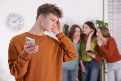 Photo of Teenage boy with smartphone suffering from bullying at school, selective focus