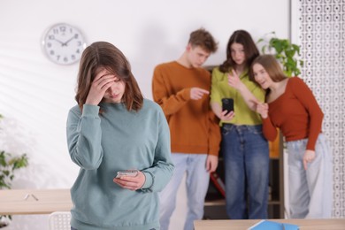 Photo of Teenage girl with smartphone suffering from bullying at school, selective focus
