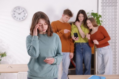 Photo of Teenage girl with smartphone suffering from bullying at school, selective focus