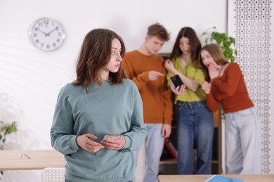 Photo of Teenage girl with smartphone suffering from bullying at school, selective focus