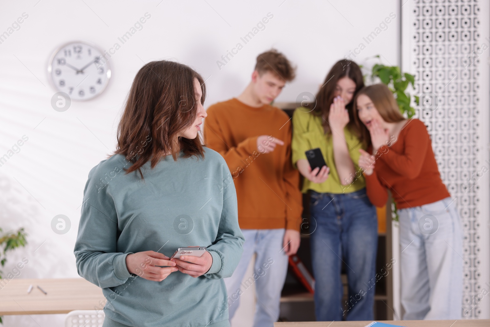 Teenage girl with smartphone suffering from bullying at school, selective focus Photo of Teenage girl with smartphone suffering from bullying at school, selective focus