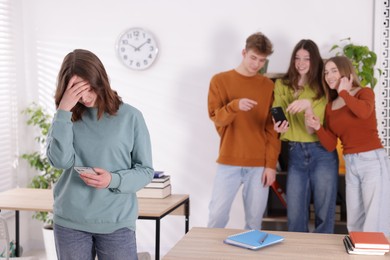 Photo of Teenage girl with smartphone suffering from bullying at school, selective focus