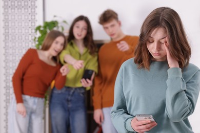 Photo of Teenage girl with smartphone suffering from bullying at school, selective focus