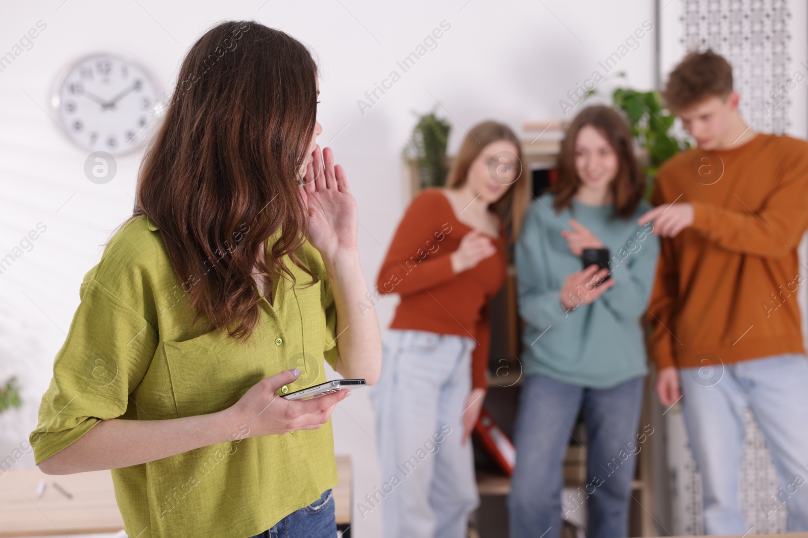 Teenage girl with smartphone suffering from bullying at school, selective focus Photo of Teenage girl with smartphone suffering from bullying at school, selective focus