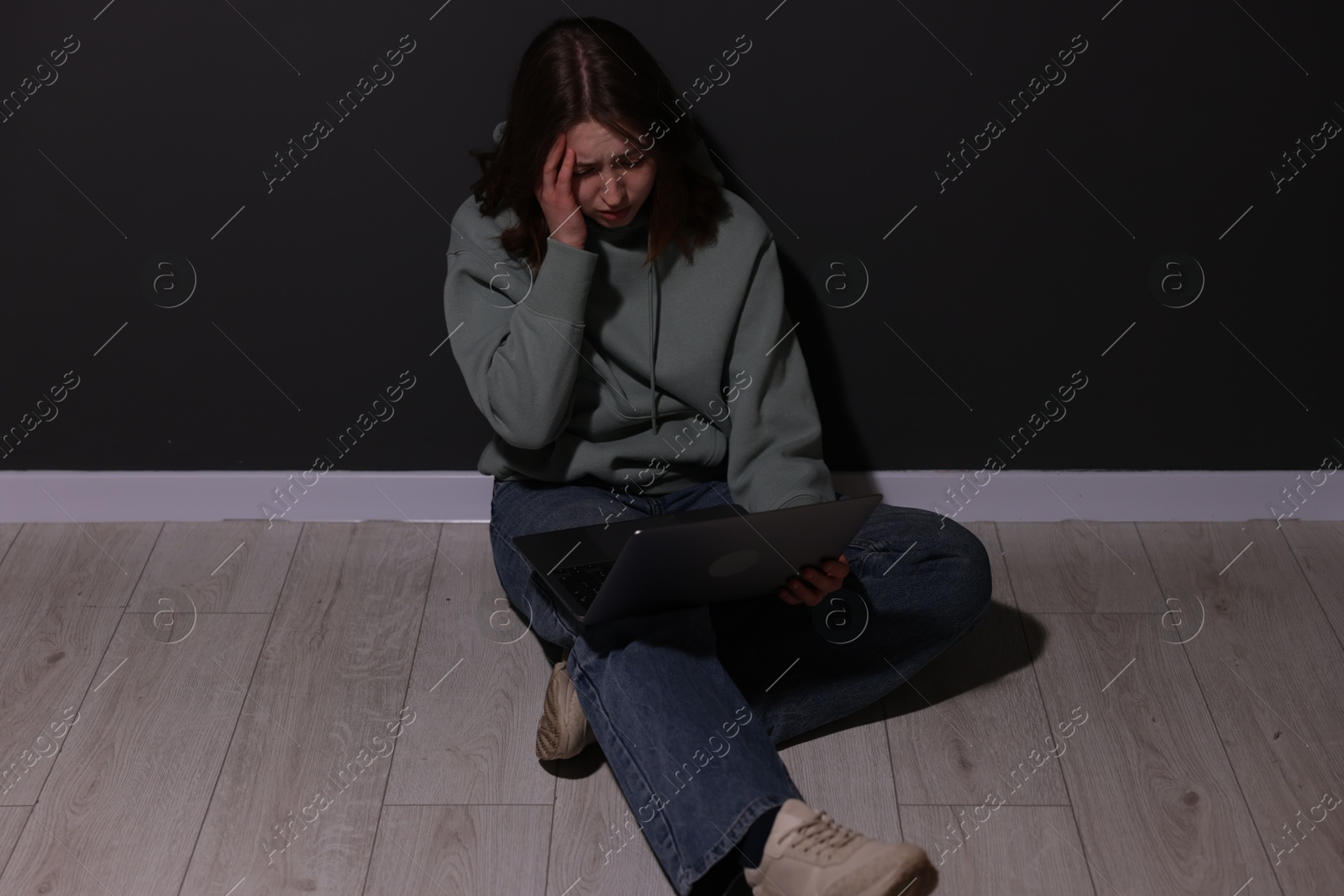 Cyber bullying. Upset teenage girl with laptop on floor indoors Photo of Cyber bullying. Upset teenage girl with laptop on floor indoors