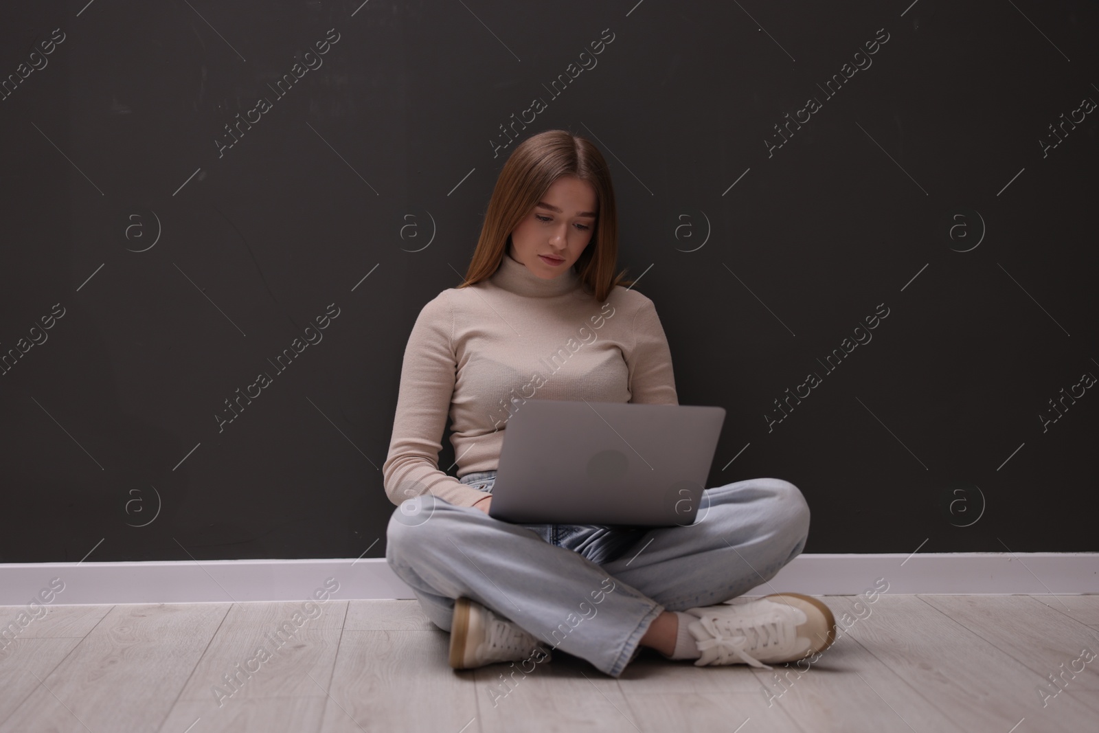 Cyber bullying. Upset teenage girl with laptop on floor indoors Photo of Cyber bullying. Upset teenage girl with laptop on floor indoors