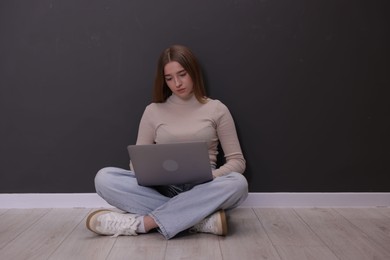 Photo of Cyber bullying. Upset teenage girl with laptop on floor indoors