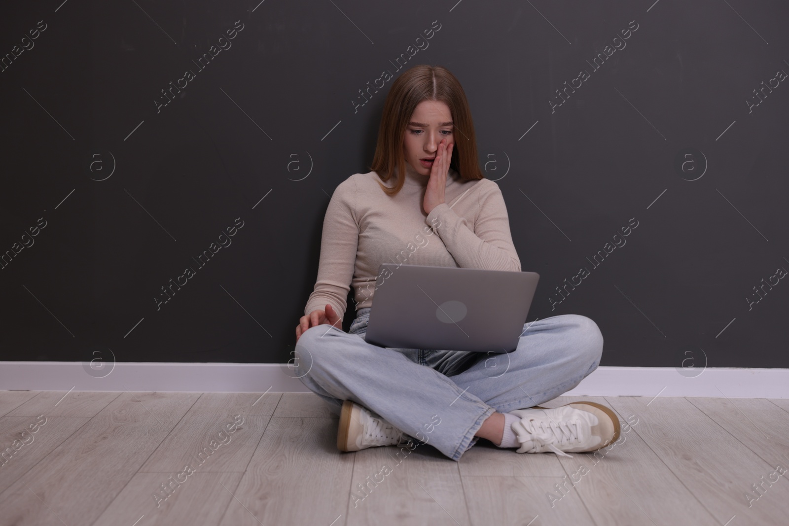 Cyber bullying. Upset teenage girl with laptop on floor indoors Photo of Cyber bullying. Upset teenage girl with laptop on floor indoors
