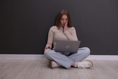 Photo of Cyber bullying. Upset teenage girl with laptop on floor indoors