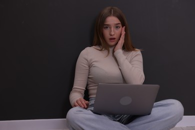 Photo of Cyber bullying. Upset teenage girl with laptop on floor indoors