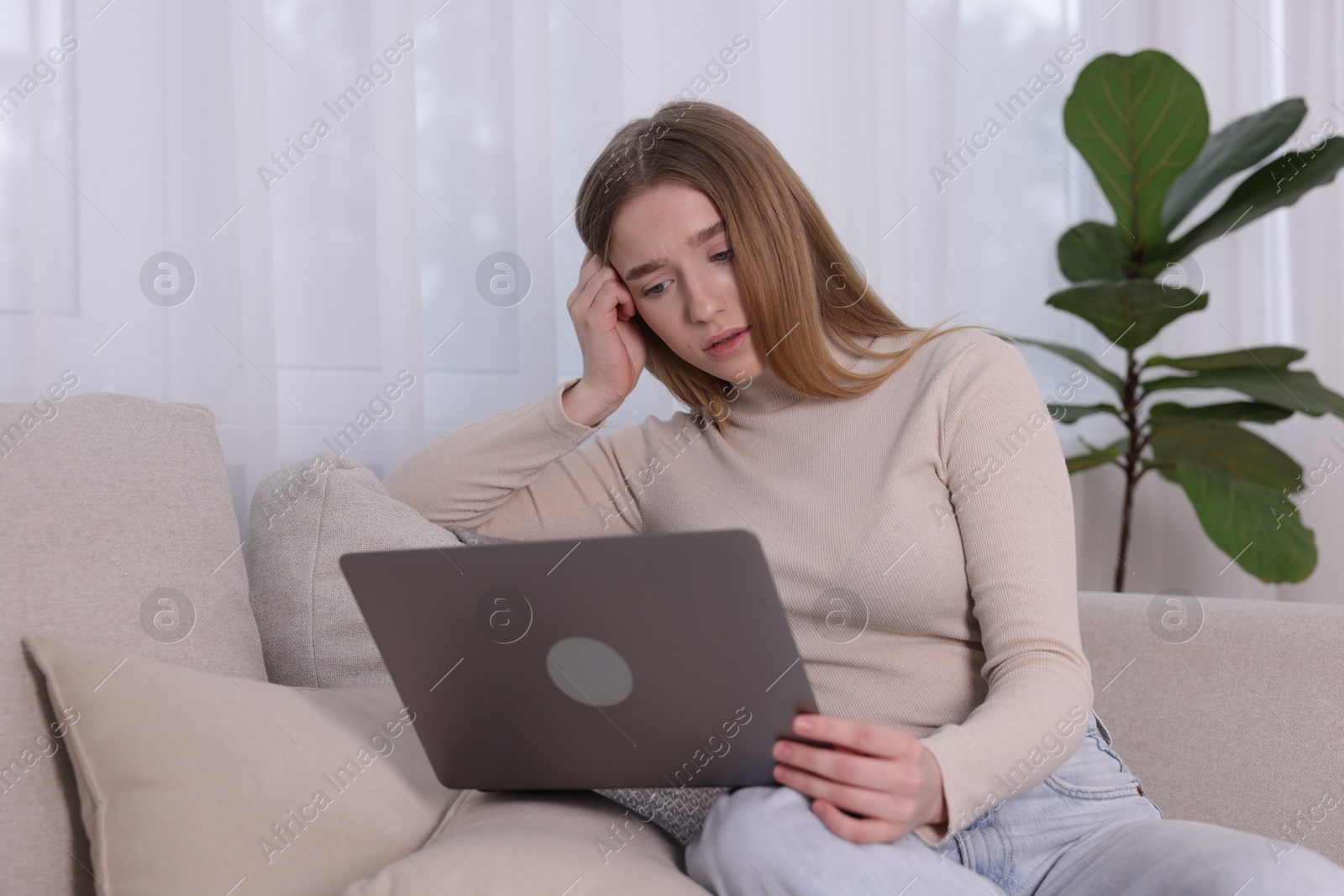 Cyber bullying. Upset teenage girl with laptop on sofa at home Photo of Cyber bullying. Upset teenage girl with laptop on sofa at home