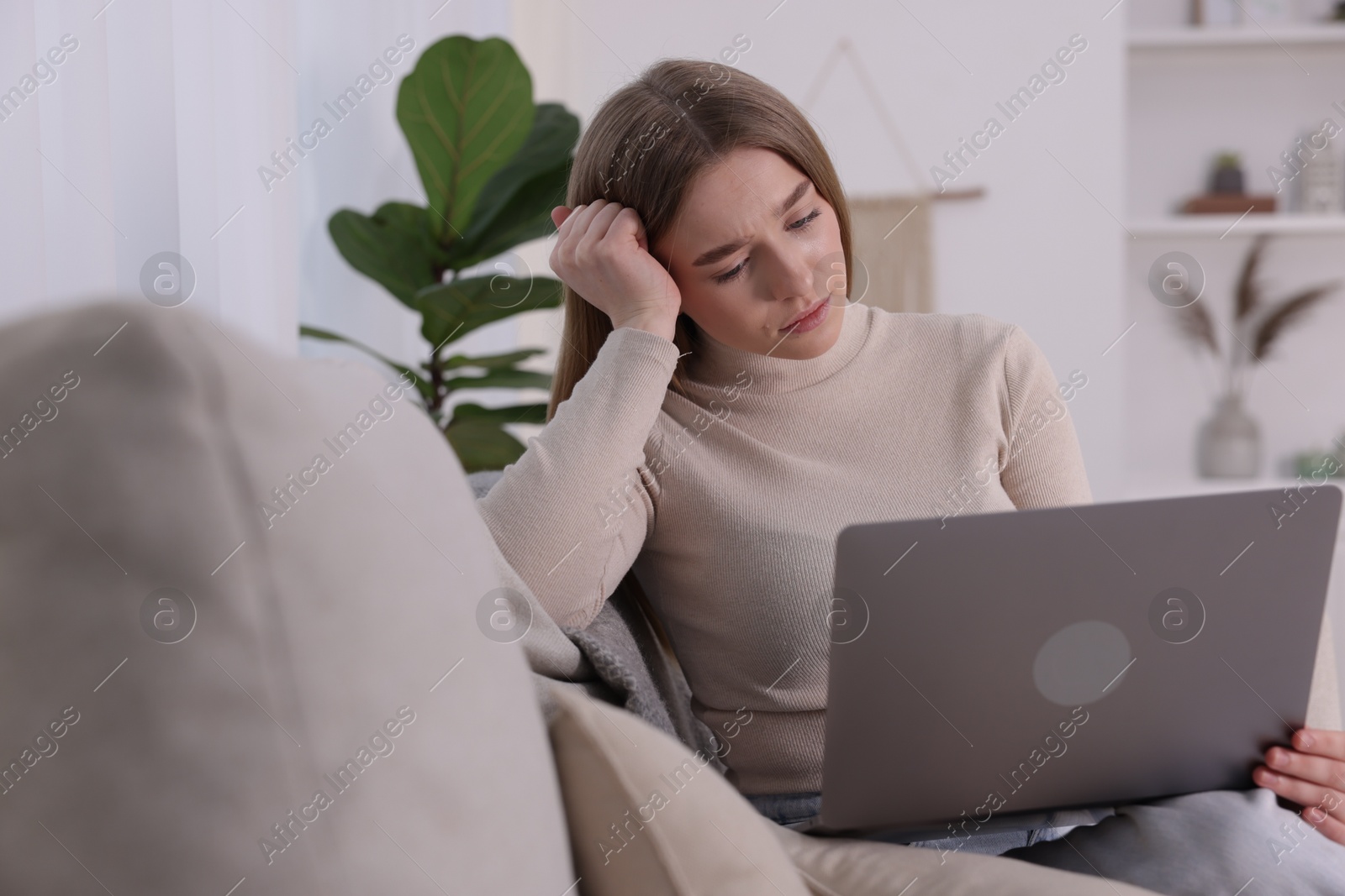 Cyber bullying. Upset teenage girl with laptop on sofa at home Photo of Cyber bullying. Upset teenage girl with laptop on sofa at home