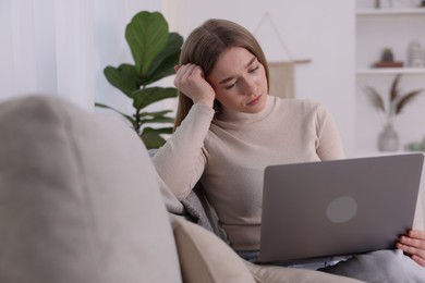 Photo of Cyber bullying. Upset teenage girl with laptop on sofa at home
