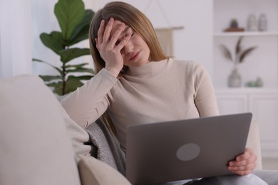 Photo of Cyber bullying. Upset teenage girl with laptop on sofa at home