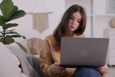 Photo of Cyber bullying. Upset teenage girl with laptop on sofa at home