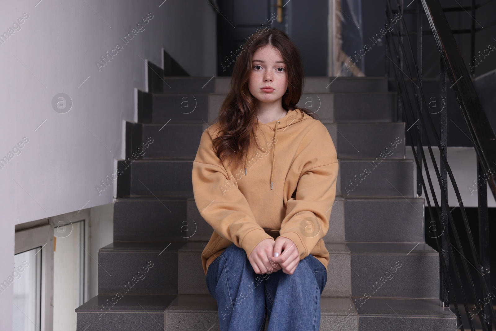 Photo of Bullying. Upset teenage girl on stairs indoors