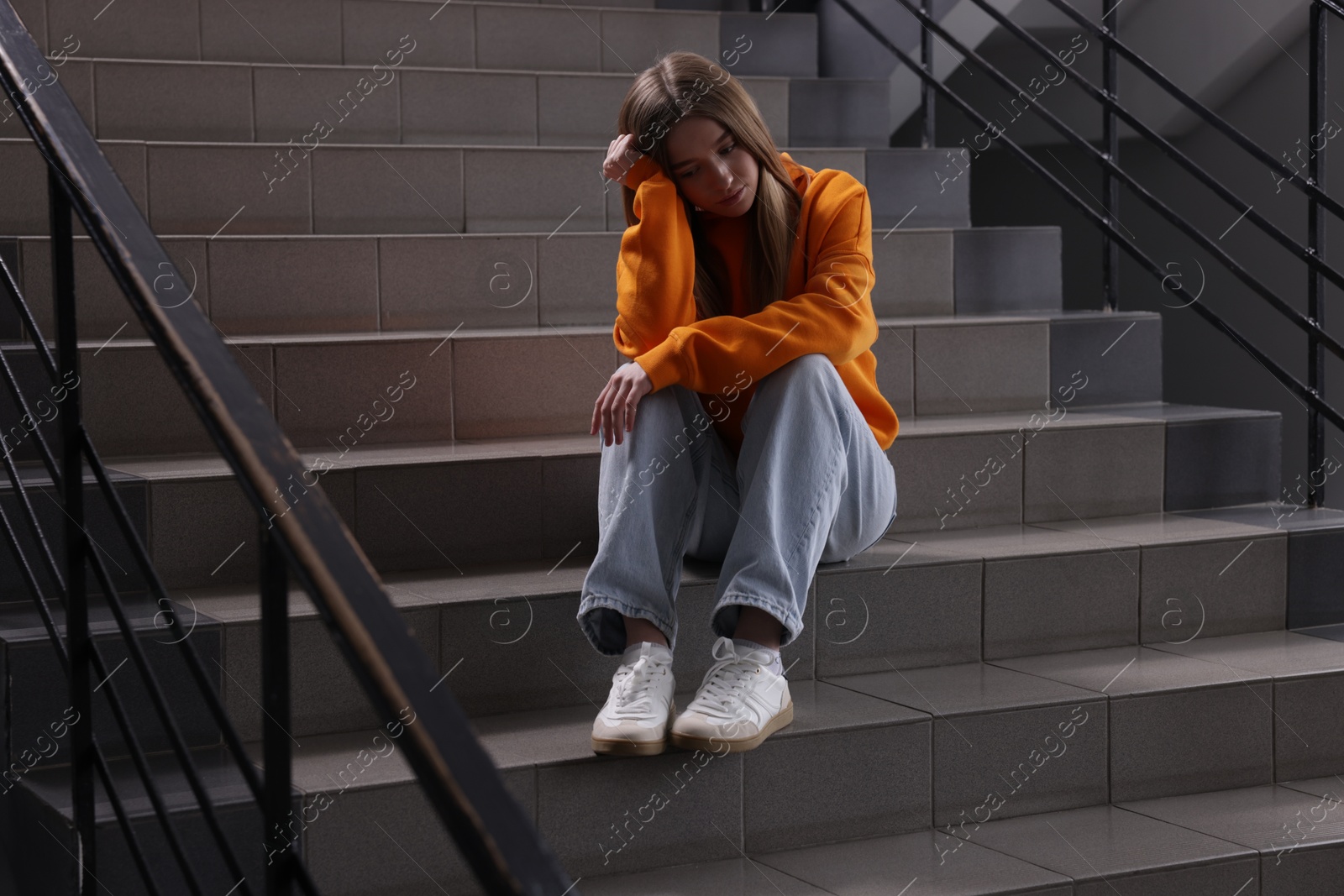 Bullying. Upset teenage girl on stairs indoors Photo of Bullying. Upset teenage girl on stairs indoors