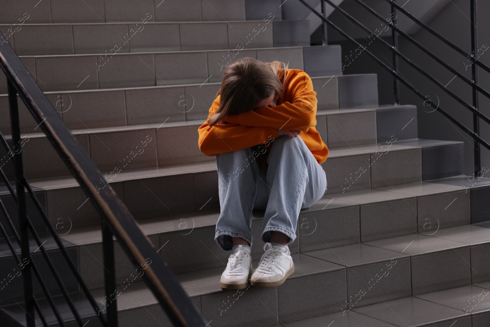 Bullying. Upset teenage girl on stairs indoors Photo of Bullying. Upset teenage girl on stairs indoors