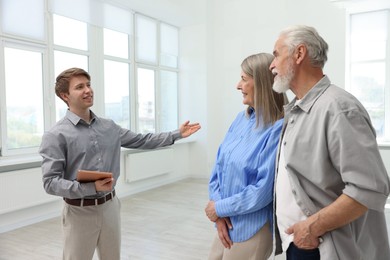 Photo of Smiling real estate agent showing apartment to couple indoors