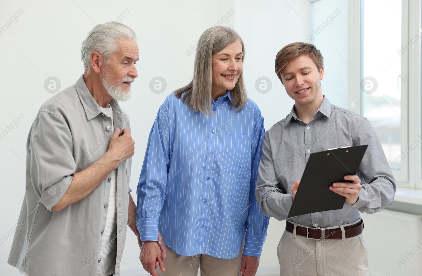 Smiling real estate agent with clipboard working with couple at home Photo of Smiling real estate agent with clipboard working with couple at home