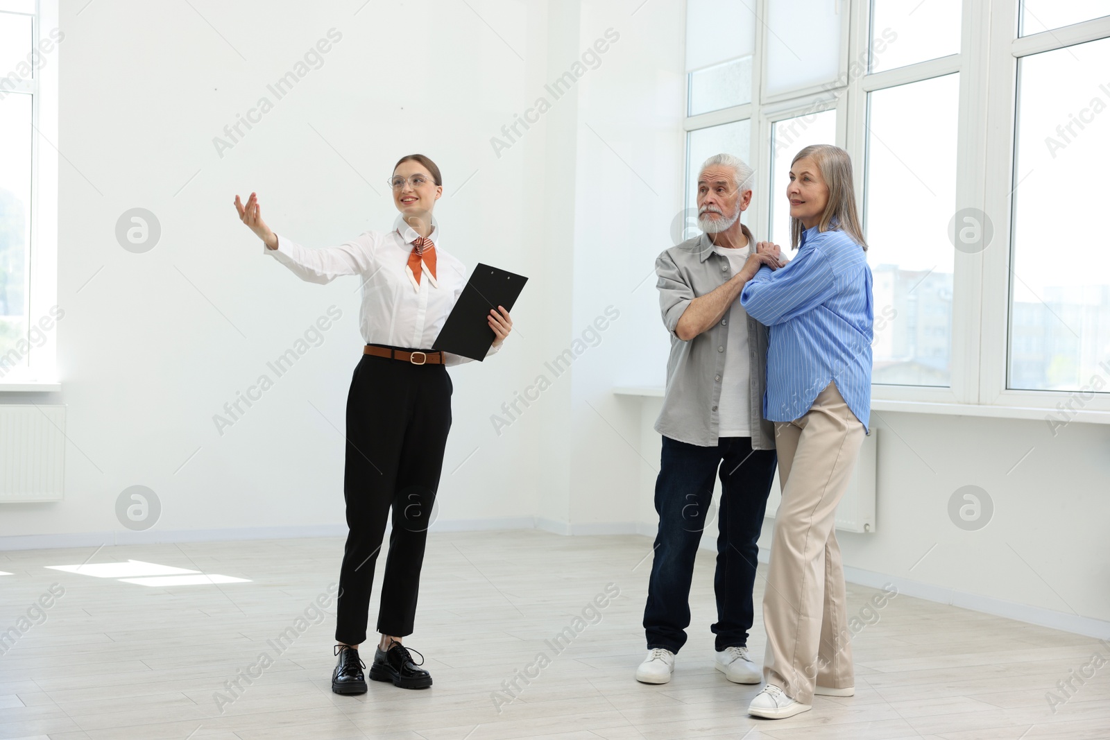 Smiling real estate agent showing apartment to couple indoors Photo of Smiling real estate agent showing apartment to couple indoors