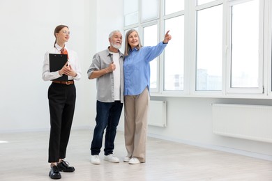 Photo of Smiling real estate agent with clipboard and couple at home