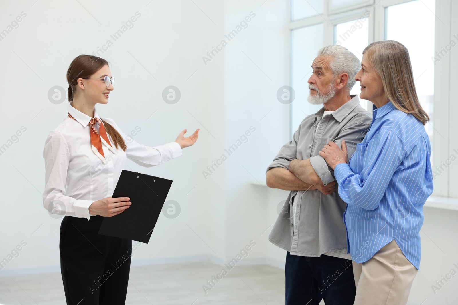 Smiling real estate agent showing apartment to couple indoors Photo of Smiling real estate agent showing apartment to couple indoors