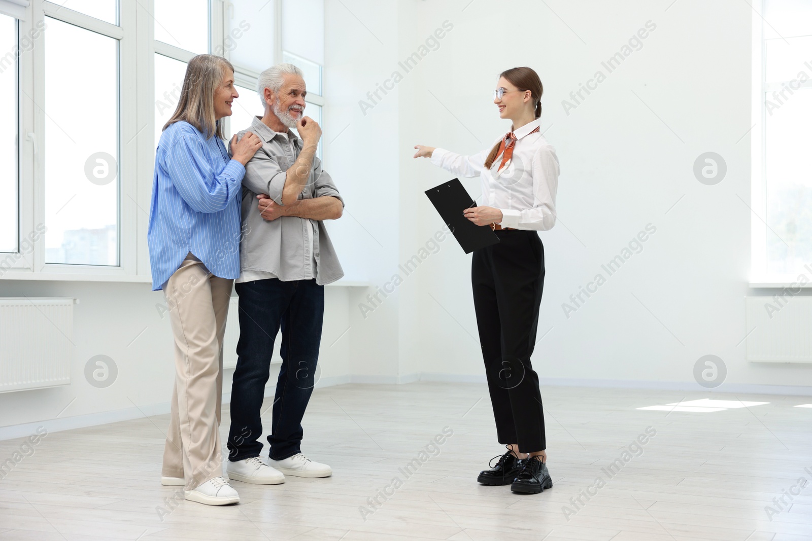 Smiling real estate agent showing apartment to couple indoors Photo of Smiling real estate agent showing apartment to couple indoors