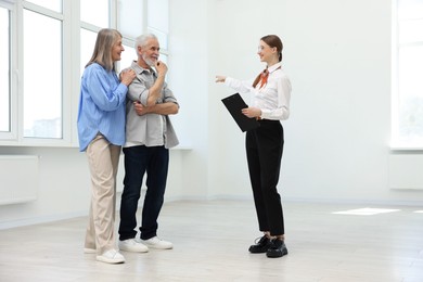 Photo of Smiling real estate agent showing apartment to couple indoors