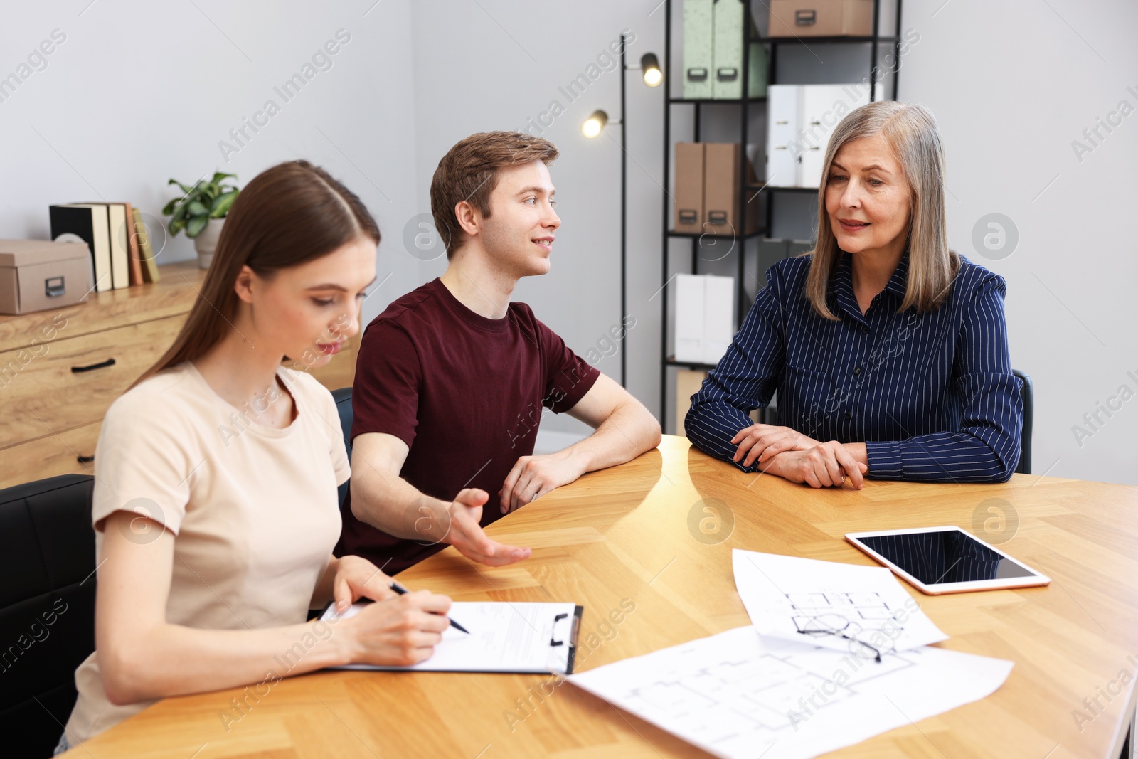 Real estate agent working with couple at table in office Photo of Real estate agent working with couple at table in office