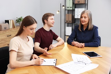 Photo of Real estate agent working with couple at table in office