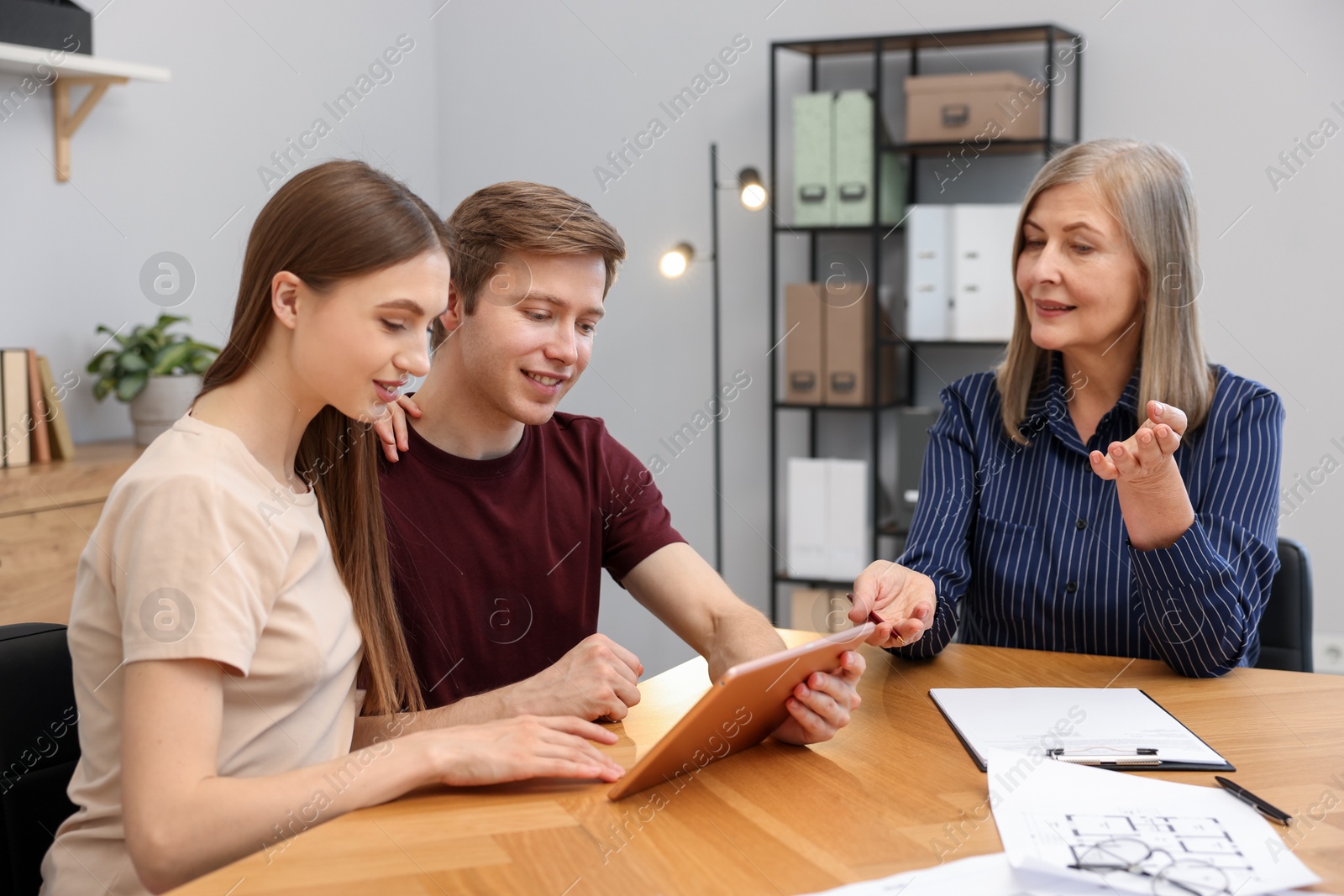 Real estate agent and couple with tablet at table in office Photo of Real estate agent and couple with tablet at table in office