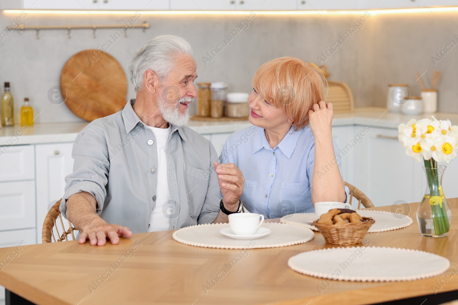 Lovely senior couple having breakfast together at wooden table in kitchen Photo of Lovely senior couple having breakfast together at wooden table in kitchen
