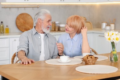 Photo of Lovely senior couple having breakfast together at wooden table in kitchen