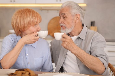Photo of Lovely senior couple having breakfast together at wooden table in kitchen