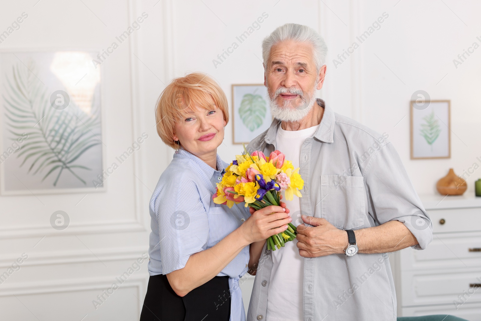 Lovely senior couple with bouquet of flowers at home Photo of Lovely senior couple with bouquet of flowers at home