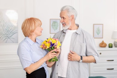 Photo of Lovely senior couple with bouquet of flowers at home