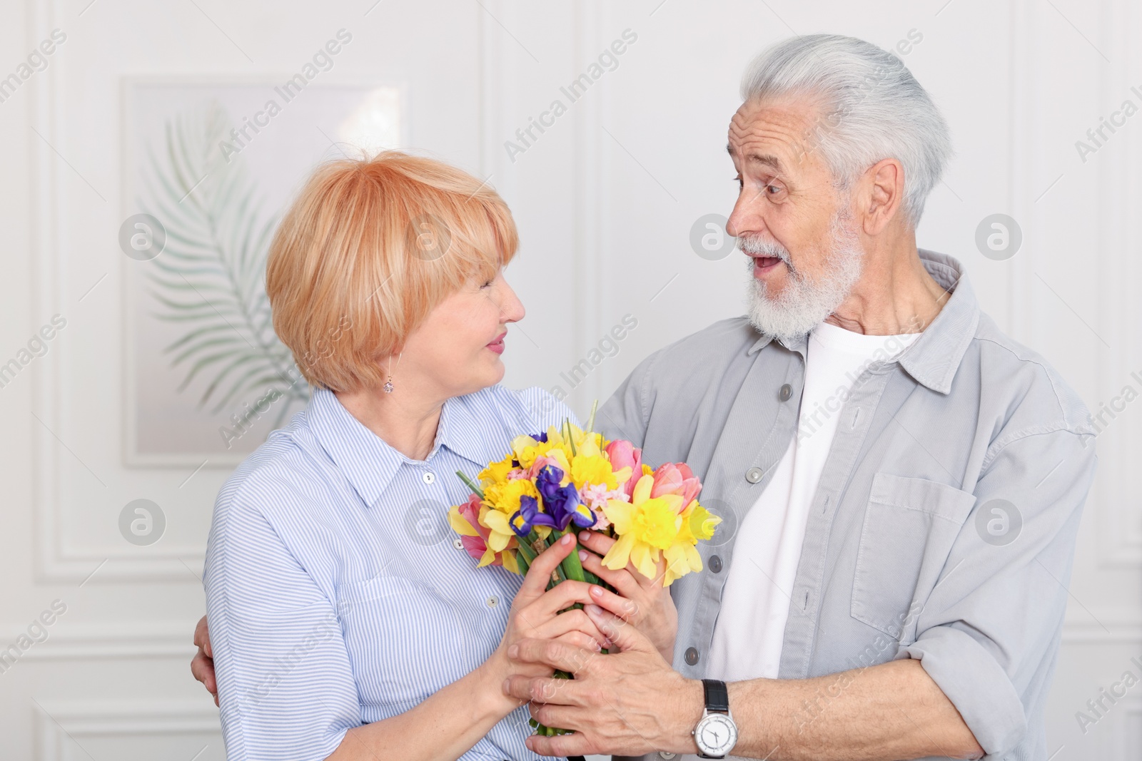 Lovely senior couple with bouquet of flowers at home Photo of Lovely senior couple with bouquet of flowers at home