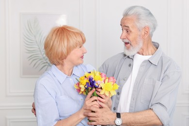 Photo of Lovely senior couple with bouquet of flowers at home