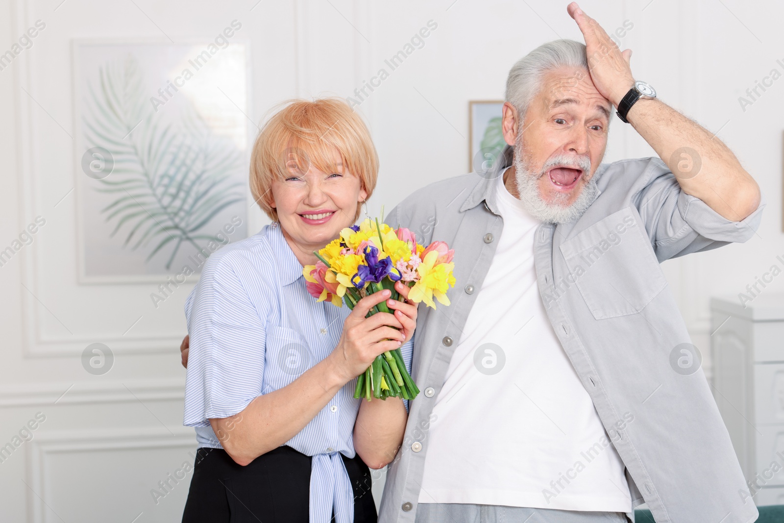 Lovely senior couple with bouquet of flowers at home Photo of Lovely senior couple with bouquet of flowers at home