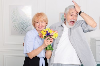 Photo of Lovely senior couple with bouquet of flowers at home