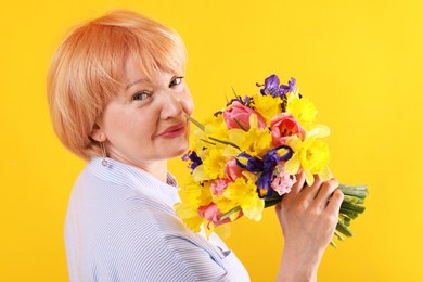 Photo of Senior woman with bouquet of flowers on yellow background