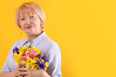 Photo of Senior woman with bouquet of flowers on yellow background, space for text