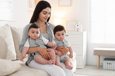 Photo of Mother with her cute twin babies on sofa at home