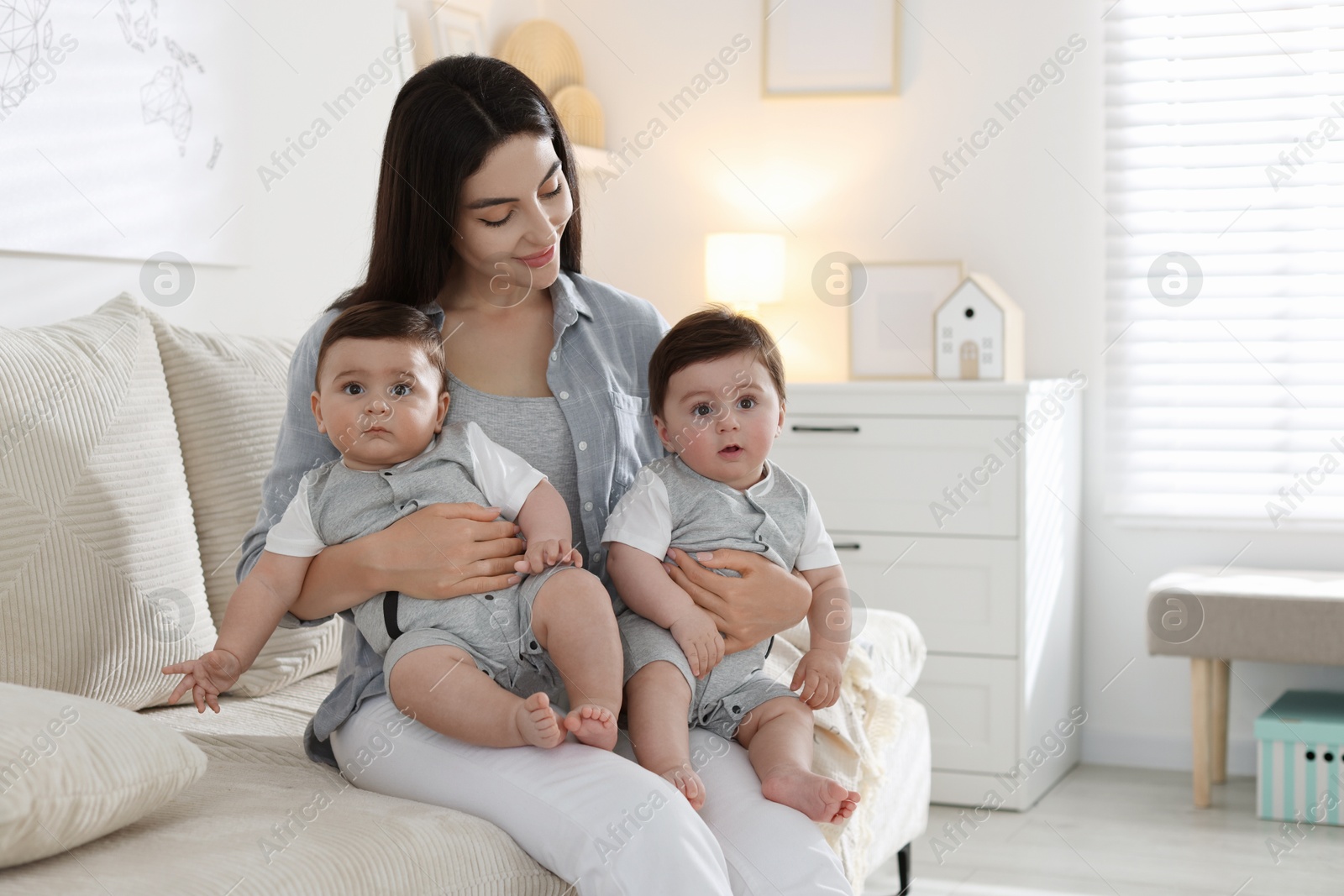 Mother with her cute twin babies on sofa at home Photo of Mother with her cute twin babies on sofa at home