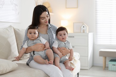 Photo of Mother with her cute twin babies on sofa at home